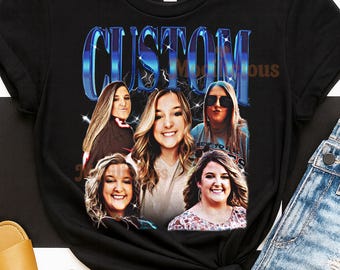 May include: Black t-shirt with a custom design featuring the word "CUSTOM" in a blue retro font. The design includes five smiling faces. The shirt is styled with denim shorts and tan sandals.