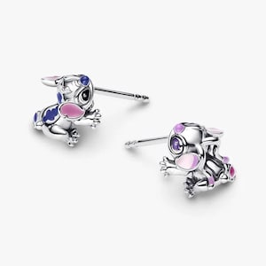 Peut inclure: Une paire de boucles d'oreilles clous argent&eacute;es repr&eacute;sentant un personnage de dessin anim&eacute;. Les boucles d'oreilles pr&eacute;sentent des d&eacute;tails en &eacute;mail bleu, rose et violet. Fond blanc.