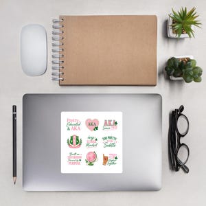Könnte beinhalten: Ein quadratischer Aufkleberbogen mit neun verschiedenen Designs in rosa und grüner Schrift und Grafik. Die Designs enthalten Phrasen wie Pretty Educated & AKA, AKA Since 1908, Ivy League Mindset, Too Pretty To Be Subtle, Built on Sisterhood Powered by Purpose und Pinkies Up Higher Together.