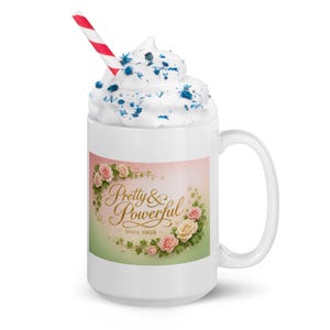 Puede incluir: Taza de cerámica blanca con asa, cubierta con crema batida y una pajita a rayas rojas y blancas. La taza presenta un diseño floral con las palabras "Pretty & Powerful Since 1908".