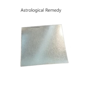 Puede incluir: Un objeto cuadrado de color plateado con el texto "Astrological Remedy" en la parte superior. El objeto tiene una superficie texturizada y las palabras "SJ Shree Jewelers" están impresas en la esquina superior izquierda.