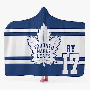 May include: A hooded blanket in blue and white, featuring the Toronto Maple Leafs logo and the number 17. The logo is a white maple leaf with the team name. The blanket has horizontal white stripes.