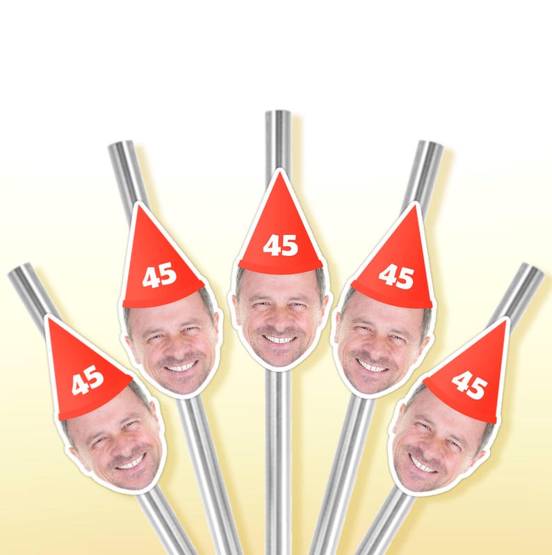 May include: A set of five stainless steel straws, each topped with a red party hat featuring the number "45" and a smiling face. The straws are arranged in a fan shape against a gradient yellow background.