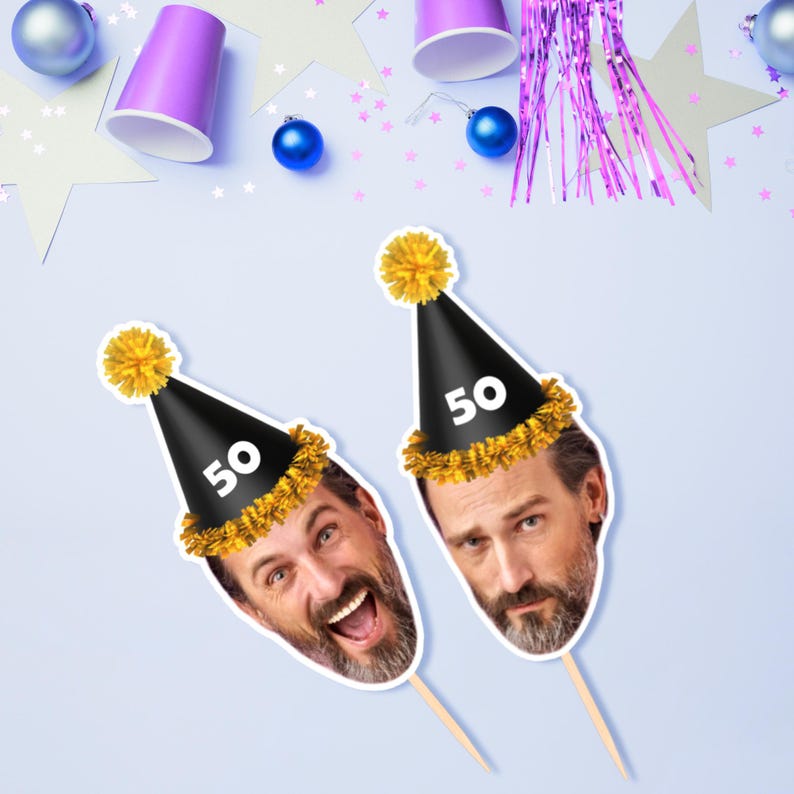 Puede incluir: Dos recortes de caras con un gorro de fiesta negro con un pomp&oacute;n amarillo y el n&uacute;mero 50. Los recortes est&aacute;n sobre palitos de madera. El fondo tiene decoraciones de fiesta, incluyendo vasos morados, adornos azules y confeti en forma de estrella.
