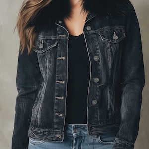 May include: A dark wash denim jacket with a black faux fur collar. The jacket has silver buttons and two chest pockets. The model is wearing a black top and blue jeans.