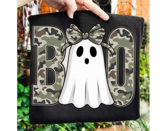 Op de afbeelding: Zwart sweatshirt met een witte spookafbeelding met een camouflage strik. Het woord "BOO" staat in grote letters met een camouflagepatroon. Een hand houdt het sweatshirt vast.