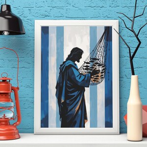 Puede incluir: Una impresión enmarcada representa una figura con una túnica azul sosteniendo una red de pesca llena de peces. El fondo presenta rayas verticales azules y blancas. La obra de arte se exhibe en un estante blanco contra una pared de ladrillos azules.