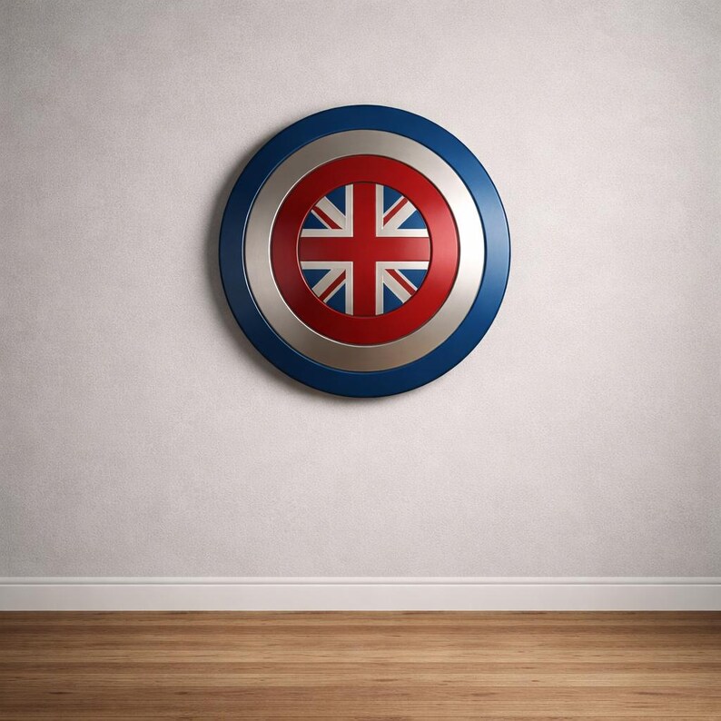 May include: A circular shield featuring the Union Jack flag at its centre. The shield has a blue outer rim, a silver middle section, and a red inner circle. It is mounted on a white wall above a wooden floor.