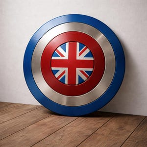 May include: A circular shield featuring the Union Jack flag at its centre, surrounded by a red ring, a silver ring, and a blue outer ring. The shield is displayed against a white wall and wooden floor.