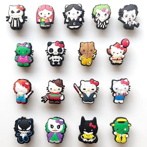 May include: A collection of black and white shoe charms featuring various characters, including a skeleton, a vampire, and a cat with a red bow. The charms are arranged on a white surface.
