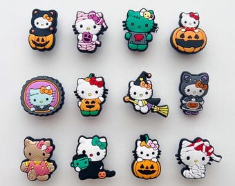 May include: A selection of twelve Halloween-themed charms featuring Hello Kitty. The charms depict Hello Kitty in various costumes, such as a witch, mummy, and Frankenstein's monster, along with pumpkins and other festive elements.