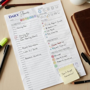 May include: A white daily planner with handwritten notes, including a schedule, to-do list, and priorities. The planner has a section for mood and weather. A yellow sticky note reads "Don't forget tomorrow!" with a pencil and pen nearby.