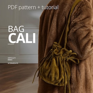 Puede incluir: En esta imagen se muestra un bolso de terciopelo color mostaza con cierre de cordón. El bolso se lleva al hombro y se combina con un abrigo de piel sintética marrón. El texto "BAG CALI" se muestra en blanco, junto con "PDF pattern + tutorial" y "Difficulty: Intermediate".