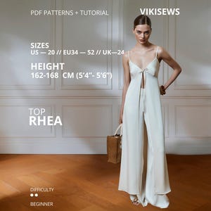 Op de afbeelding: Een vrouw draagt een witte top en een broek met wijde pijpen. De top heeft spaghettibandjes en een sleutelgatdetail. De afbeelding bevat tekst met de tekst "PDF Patterns + Tutorial", "VIKISEWS", "TOP RHEA" en informatie over maten en hoogte.