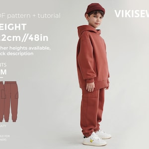May include: A young person wearing a rust-colored hoodie and matching pants. The image includes a PDF pattern and tutorial for the "SAM" pants, with a height of 122cm/48in. The text "VIKISEWS" is visible in the upper right corner. The difficulty level is suitable for beginners.
