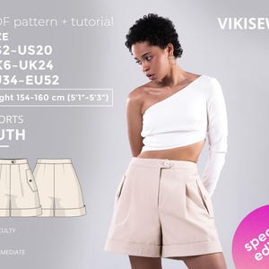 Può includere: Una donna indossa un top bianco monospalla e pantaloncini beige. L'immagine include un modello per "SHORTS RUTH" con taglie US2-US20, UK6-UK24 ed EU34-EU52. L'altezza è 154-160 cm. Il livello di difficoltà è intermedio.