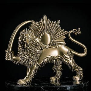 Op de afbeelding: Een goudkleurig metalen leeuwenbeeld op een ronde voet van zwart marmer. De leeuw is in profiel afgebeeld, houdt een gebogen zwaard in zijn voorpoot en heeft een zon-embleem met een centrale schijf op zijn rug.