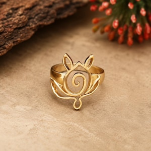 May include: A gold-toned ring featuring an openwork design on the front. The centerpiece consists of a central spiral surrounded by symmetrical, leaf-like or petal-shaped wire elements that extend upward and outward from the band.