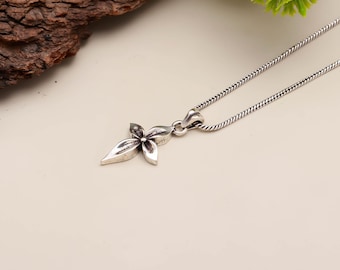 May include: A silver-toned necklace featuring a floral pendant. The pendant has a four-petal flower design with detailed textures. The chain is a delicate, twisted rope style. The necklace is displayed against a neutral background.