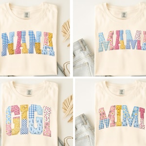 Peut inclure: Quatre t-shirts crème avec les mots "NANA", "MAMA", "GIGI" et "MIMI" en lettres patchwork colorées. Les lettres présentent des motifs floraux et vichy bleus, roses et jaunes. Les chemises sont pliées et présentées avec des jeans.