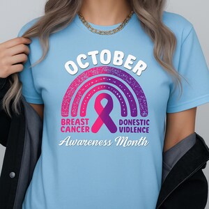 A woman wearing a blue t-shirt with a graphic design related to breast cancer awareness.