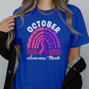 A person wearing a blue t-shirt with a graphic design related to breast cancer awareness.