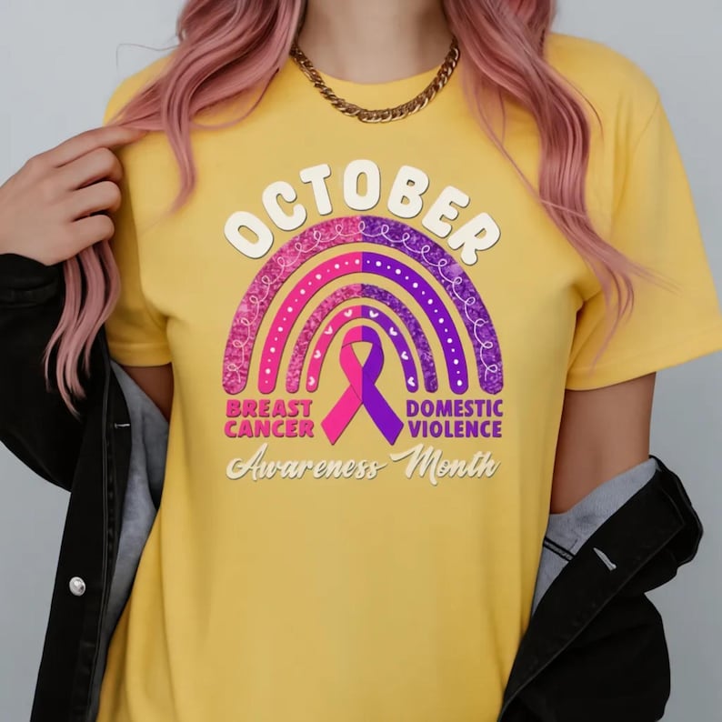 A person wearing a yellow t-shirt with a graphic design related to breast cancer awareness.