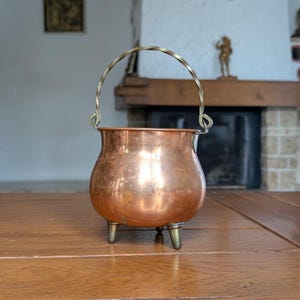 May include: A white ceramic mug with a black handle and the text "But First, Coffee" in a black, handwritten-style font. The mug is on a white surface.