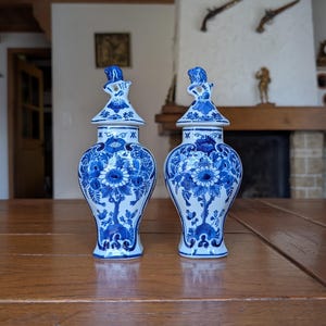 Royal Delft pair of blue lidded vases with hand-painted floral delftware design for classic shelf display or collectible porcelain decor