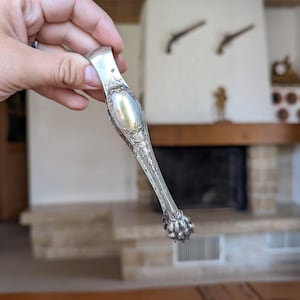 Vintage silver sugar tongs with ornate claw design for elegant tea service or antique flatware collection