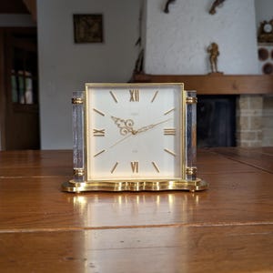 Looping 8 Days vintage 50s table alarm clock with gold-tone base and glass columns in Mid-century modern style for office desk decor