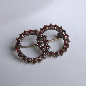 Vintage 800 silver brooch with garnet stones in intertwined ring design for antique jewelry collectors or elegant accessory display