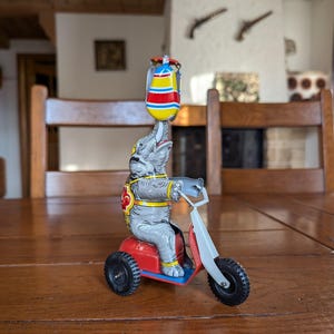 Vintage tin toy wind-up elephant on a red tricycle with spinning colorful drum circus-themed collectible figurine