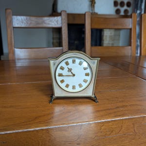 Junghans vintage brass table clock with arched case, Roman numerals, and curved legs for fireplace decor from Germany