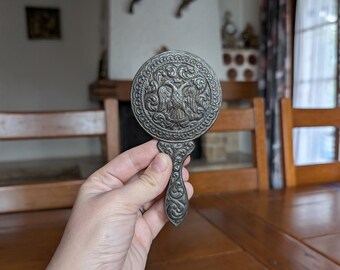 Vintage ornate hand mirror with embossed eagle emblem and decorative baroque handle
