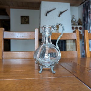 Antique glass wine pitcher with ornate metal handle and legs Art Nouveau style from early 20th century for elegant table decor