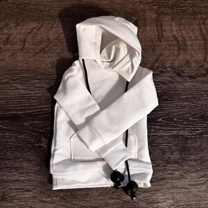 May include: A white hoodie with a drawstring and a front pocket. The hoodie has a hood and long sleeves. The drawstring is black with black ball-shaped ends. The hoodie is made of a soft, comfortable material.