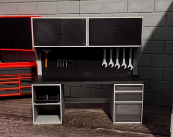 May include: A miniature workshop set in black and white. The set features a workbench with cabinets, drawers, and a pegboard with tools. A red toolbox is visible in the background.