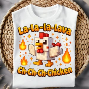Puede incluir: Camiseta blanca con un diseño de pollo pixelado y el texto "La-la-la-lava Ch-ch-ch-chicken" en naranja y amarillo. El diseño incluye llamas y símbolos de cruz.