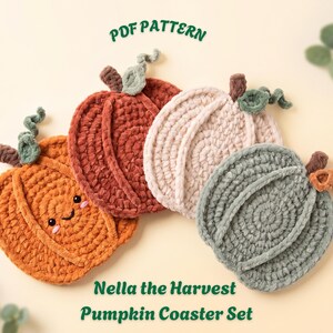 Peut inclure: Un ensemble de quatre dessous de verre en crochet en forme de citrouille, aux couleurs orange, rouille, crème et vert sauge. La citrouille orange a un visage souriant avec des joues roses. Chaque pièce a une tige brune et une vrille verte. Texte : PDF PATTERN Nella the Harvest Pumpkin Coaster Set.