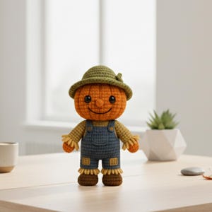 May include: A handmade crochet pumpkin doll wearing a green hat and denim overalls. The doll has a smiling face and brown boots. It is a fall-themed decorative item.