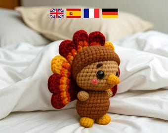 May include: A handmade crochet turkey figurine with a brown body, a tan head, and a vibrant fan of red, orange, and yellow feathers. The turkey has a small yellow beak, black eyes, and a pink blush. It is a cute, whimsical decoration.