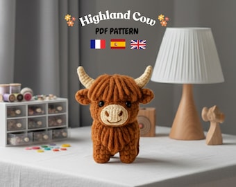 May include: A crocheted Highland cow figurine with brown fur, cream-colored horns, and a smiling face. The image includes text that reads "Highland Cow PDF Pattern" and flags of France, Spain, and the United Kingdom. The cow is on a white surface.