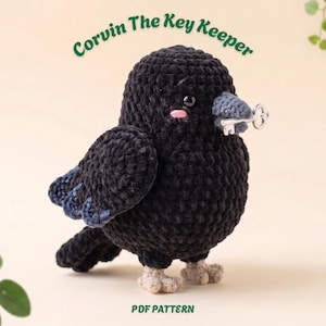 Może przedstawiać: Czarny szydełkowany pluszowy kruk z szarym dziobem trzymający mały srebrny metalowy klucz. Widoczny jest tekst Corvin The Key Keeper oraz PDF PATTERN. Kruk ma małe czarne oczy, różowe policzki i jasnobeżowe stopy.