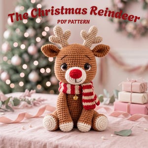 May include: A brown crocheted reindeer toy with a red nose, light-colored antlers, and a red and white striped scarf featuring a small gold bell. The text The Christmas Reindeer PDF PATTERN is displayed at the top of the image.