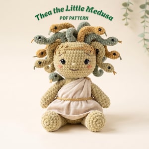 Puede incluir: Una muñeca de ganchillo llamada Thea the Little Medusa PDF Pattern con cuerpo de hilo verde claro, toga de tela beige con cinturón trenzado dorado y cabeza adornada con varias serpientes pequeñas de hilo beige y verde y una diadema dorada.