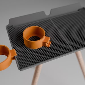 Peut inclure: Un plateau rectangulaire gris avec une surface textur&eacute;e en nid d'abeille et deux porte-gobelets circulaires orange fix&eacute;s sur les c&ocirc;t&eacute;s. Le plateau est soutenu par des pieds en bois clair, offrant une plateforme stable pour les boissons.
