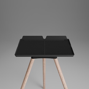 Peut inclure: Un plateau rectangulaire noir avec une surface &agrave; grille textur&eacute;e et un bord sur&eacute;lev&eacute;, soutenu par trois pieds en bois clair. Le plateau pr&eacute;sente un design divis&eacute; en deux sections distinctes avec une petite encoche au centre du rebord arri&egrave;re.