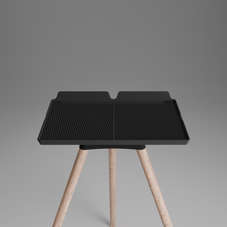 Peut inclure: Un plateau rectangulaire noir avec une surface &agrave; grille textur&eacute;e et un bord sur&eacute;lev&eacute;, soutenu par trois pieds en bois clair. Le plateau pr&eacute;sente un design divis&eacute; en deux sections distinctes avec une petite encoche au centre du rebord arri&egrave;re.