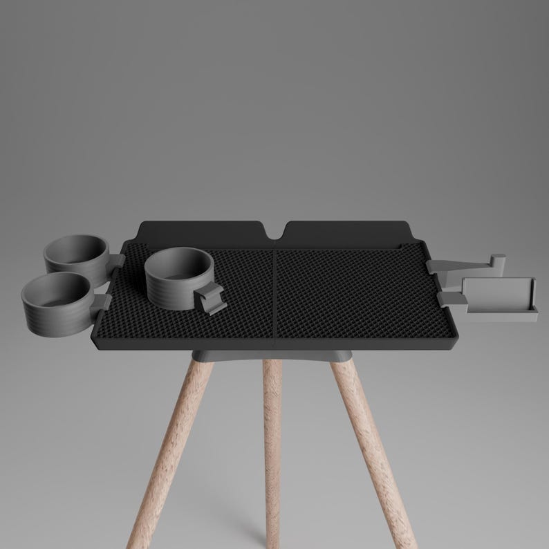 Peut inclure: Un plateau rectangulaire noir &agrave; surface textur&eacute;e, dot&eacute; de trois porte-gobelets fix&eacute;s sur le c&ocirc;t&eacute; gauche et d'un petit compartiment rectangulaire sur le c&ocirc;t&eacute; droit, soutenu par trois pieds en bois clair dispos&eacute;s en tr&eacute;pied.
